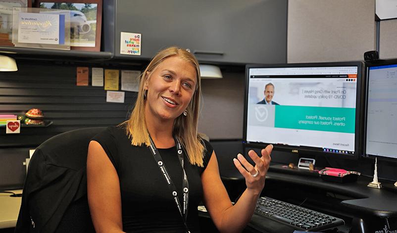 Piper, sitting at her desk, smiling and talking to someone behind the camera